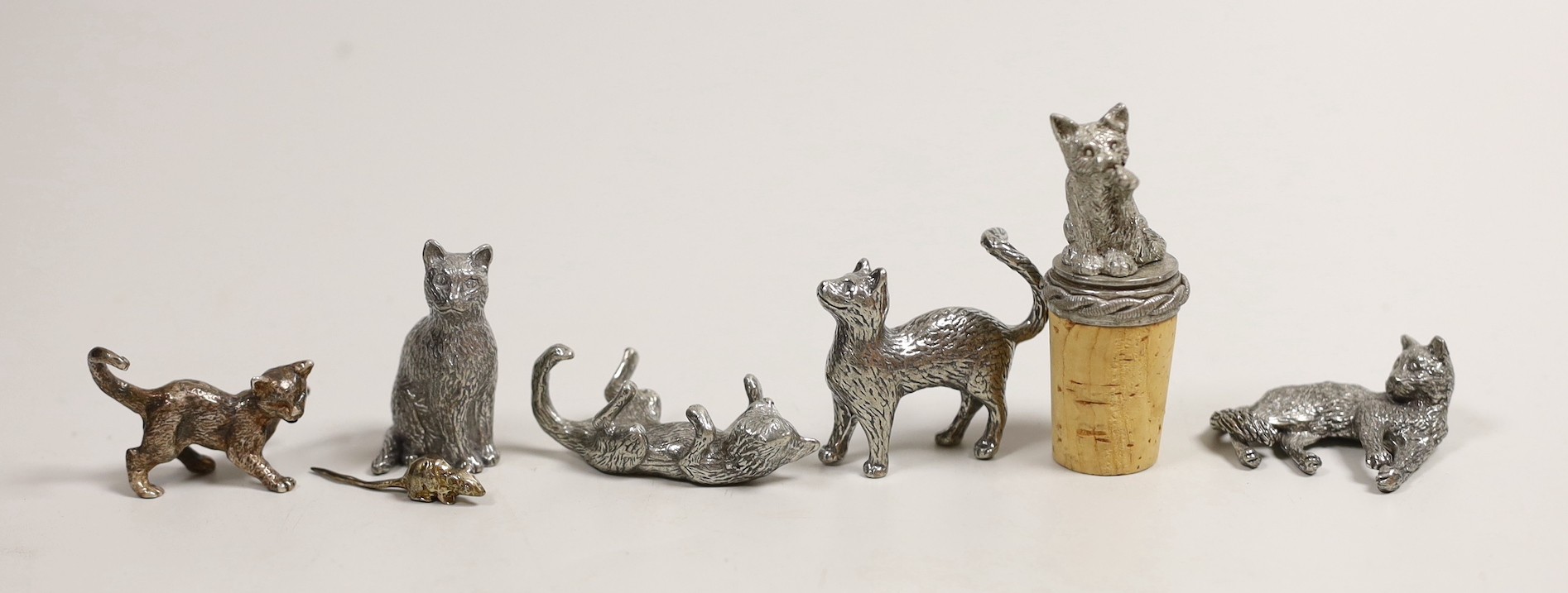 A modern silver miniature free standing model of a cat, with raised paw, London, 1995, length 37mm, together with four other base metal cats and a mouse and a cork stopper with cat finial.